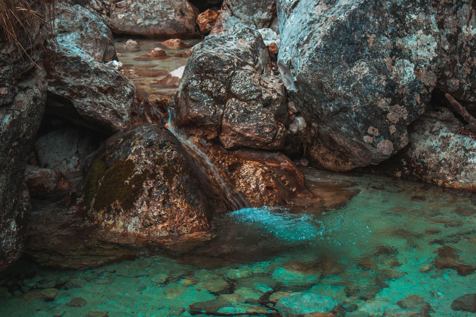 A small clear stream running over moss-covered rocks in woodland
